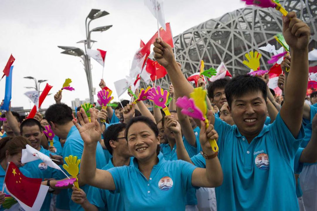 (Getty) Volunteers react in front of journalists a few minutes before the announcement by the International Olympic Committee voting for Beijing to host the 2022 Winter Olympics in Beijing on July 31, 2015.